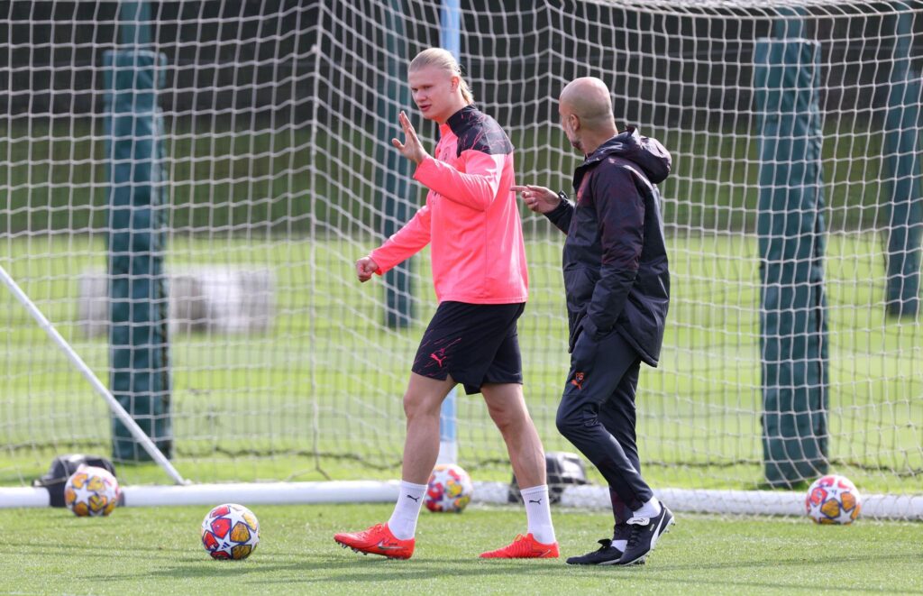 Erling Haaland échangeant avec Pep Guardiola pendant un entraînement de Manchester City, pour illustrer la préparation, la concentration et la productivité.
